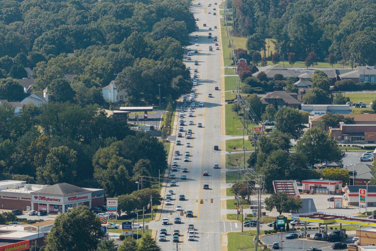 A retail corridor at Five Forks in Greenville County, shopfronts and parking on either side and traffic in both directions.