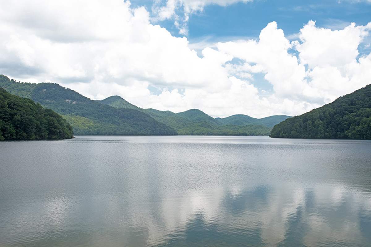 North Saluda reservoir in northern Greenville County, ringed by forested ridges under a bright sky.