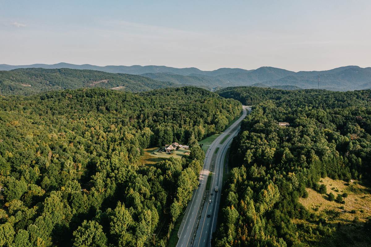 A highway curving through forested hills in northern Greenville County, with the Blue Ridge escarpment on the horizon.